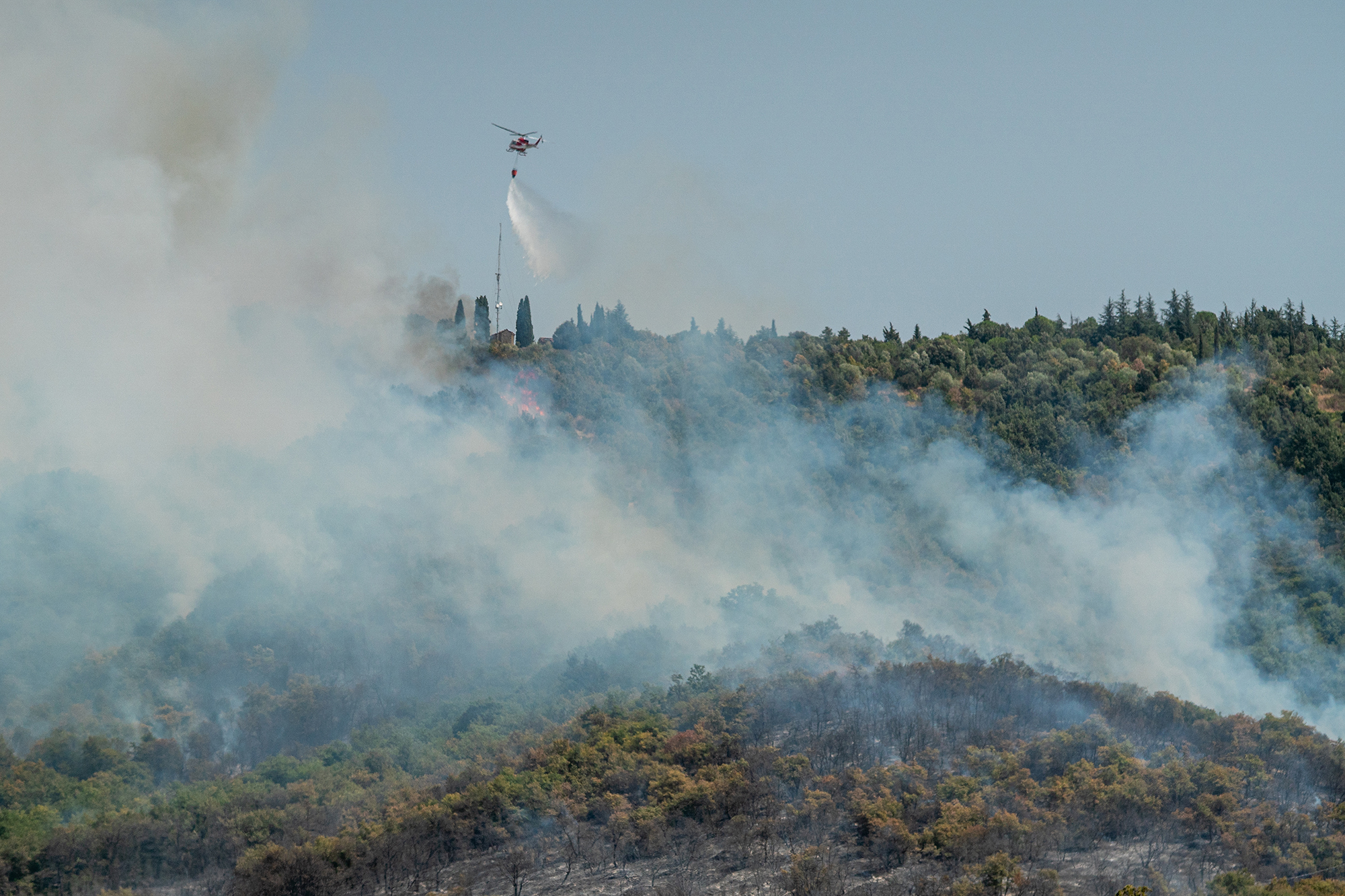 Firefighting Aircraft dropping the water for fighting a fire on mountain above Lake Ghirla in Valganna, province of Varese, Italy
